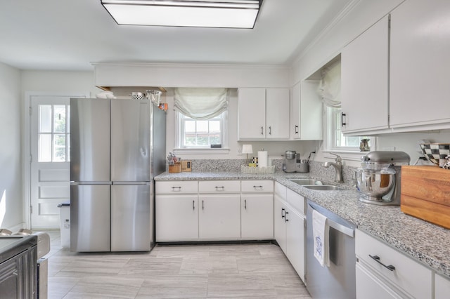 kitchen featuring appliances with stainless steel finishes, light stone counters, white cabinetry, and sink