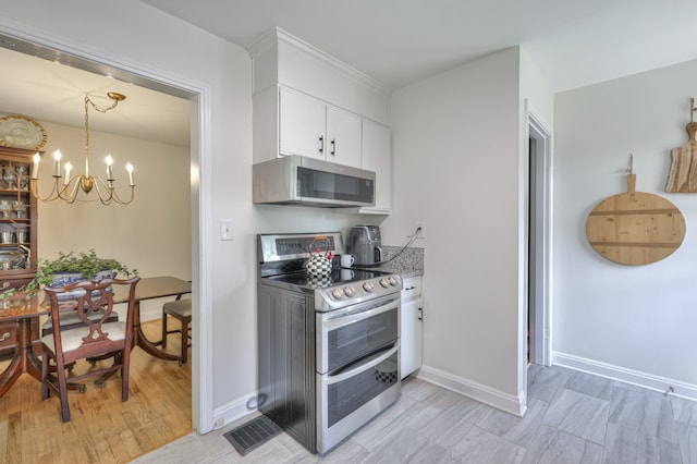 kitchen with white cabinets, appliances with stainless steel finishes, light hardwood / wood-style floors, and a notable chandelier