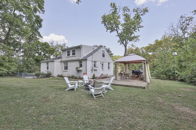 back of property with a fire pit, a lawn, a gazebo, and a deck