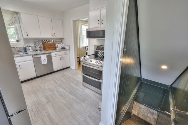 kitchen featuring a wealth of natural light, stainless steel appliances, and white cabinetry