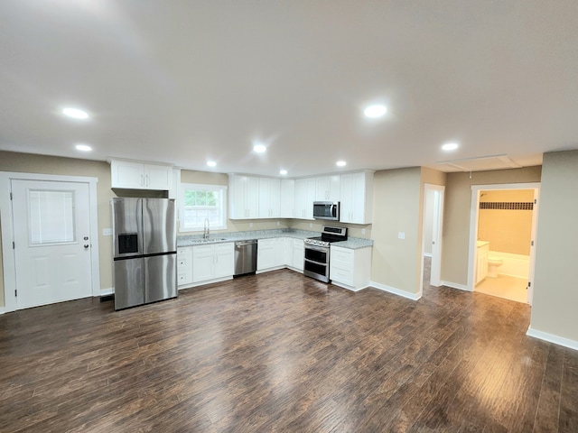 kitchen with appliances with stainless steel finishes, white cabinetry, dark hardwood / wood-style floors, and sink