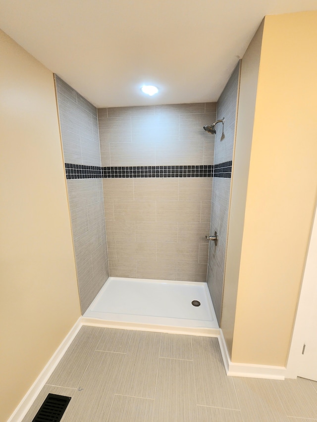 bathroom with tile patterned flooring and a tile shower