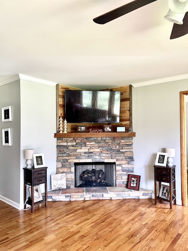 living room featuring a fireplace, ornamental molding, wood-type flooring, and ceiling fan