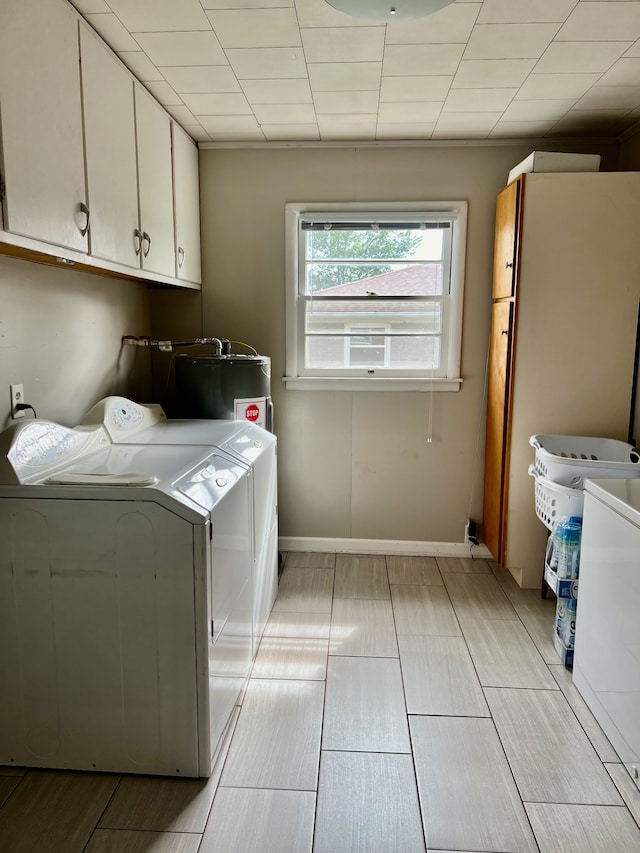 laundry room featuring electric water heater, cabinets, and separate washer and dryer