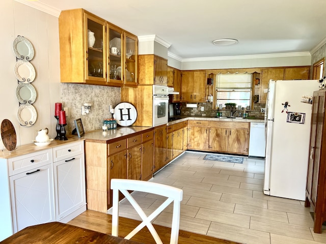 kitchen featuring white appliances, light hardwood / wood-style flooring, ornamental molding, sink, and decorative backsplash