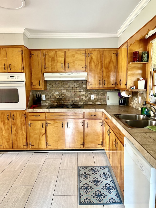 kitchen featuring ornamental molding, backsplash, sink, and white appliances