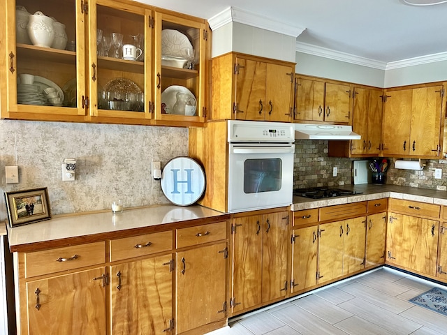 kitchen featuring light wood-type flooring, ornamental molding, white oven, decorative backsplash, and black gas cooktop