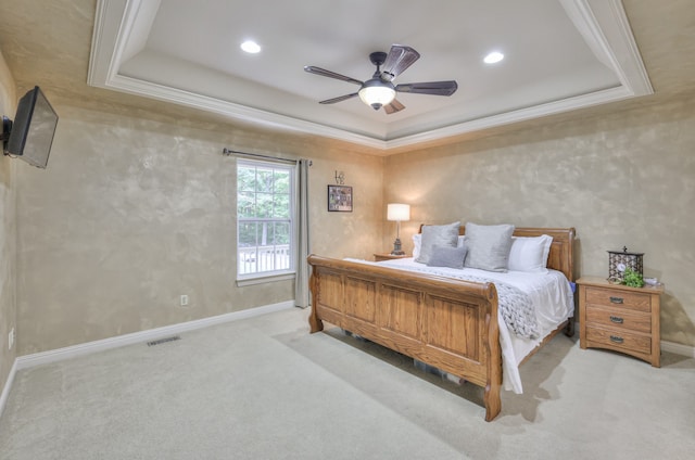 carpeted bedroom featuring a tray ceiling, ornamental molding, and ceiling fan