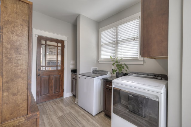 clothes washing area with cabinets, light hardwood / wood-style floors, and washer and clothes dryer