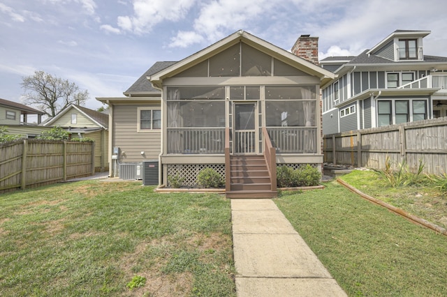 rear view of house with a lawn and a sunroom