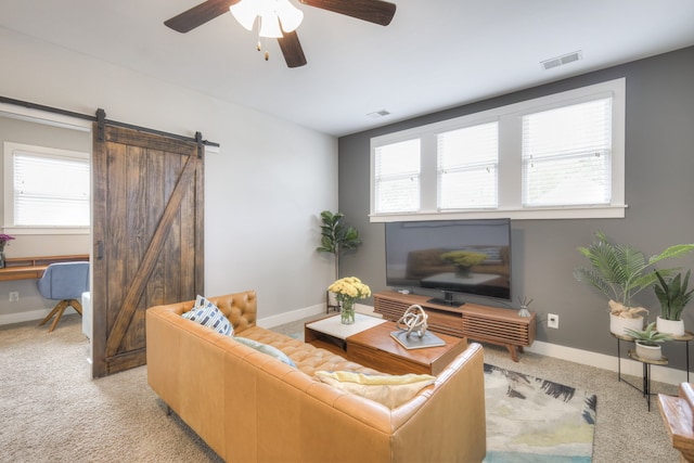 carpeted living room featuring a wealth of natural light, a barn door, and ceiling fan