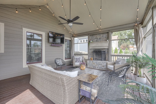 sunroom / solarium featuring ceiling fan and a fireplace