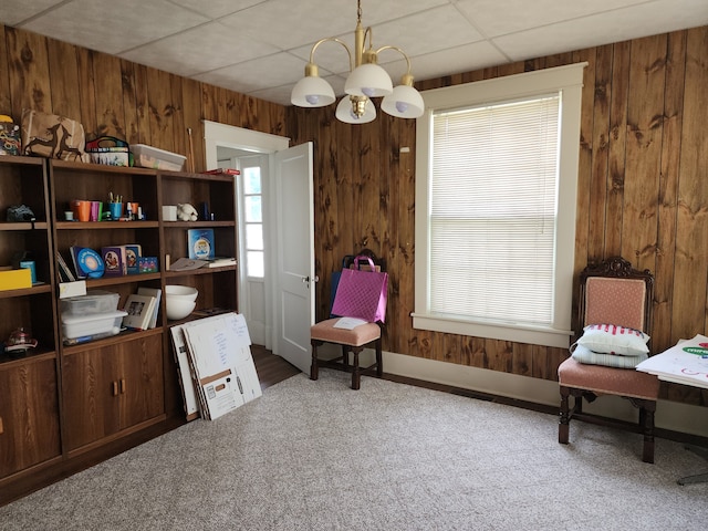 sitting room with a paneled ceiling, an inviting chandelier, carpet floors, and wooden walls