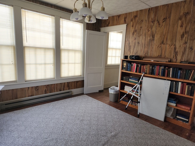 miscellaneous room featuring a baseboard heating unit, dark hardwood / wood-style flooring, an inviting chandelier, and wood walls