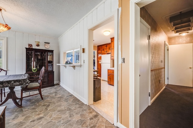 hallway with stone floors and a textured ceiling