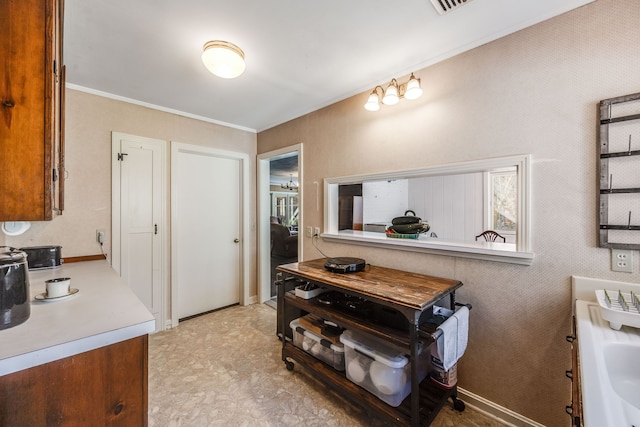 kitchen featuring light countertops, brown cabinetry, and crown molding