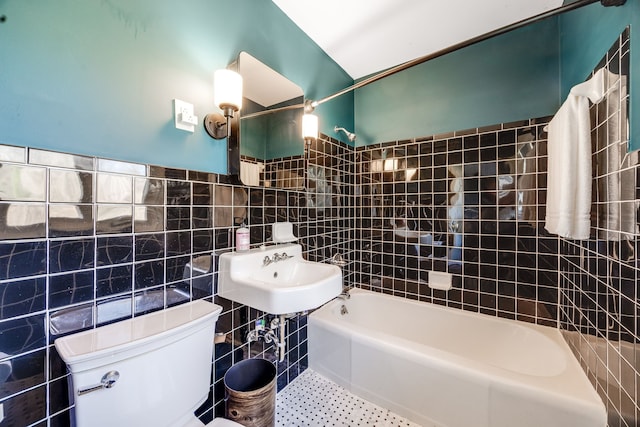 full bath featuring tile walls, toilet, tile patterned flooring, shower / bathtub combination, and a sink