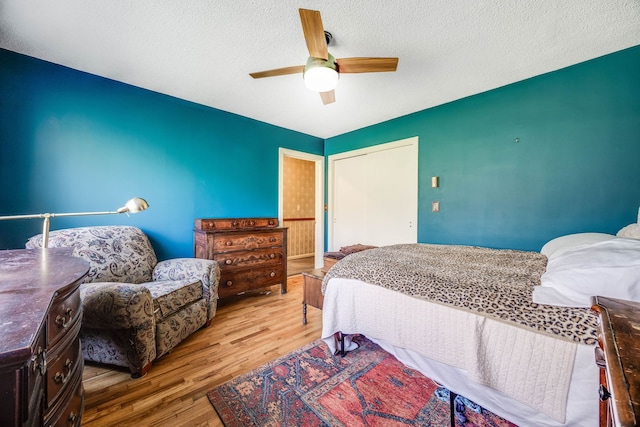 bedroom with a ceiling fan, a textured ceiling, and wood finished floors