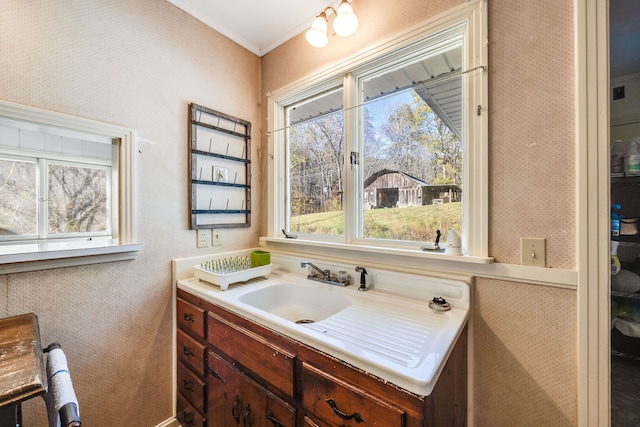 bathroom featuring ornamental molding, vanity, and wallpapered walls