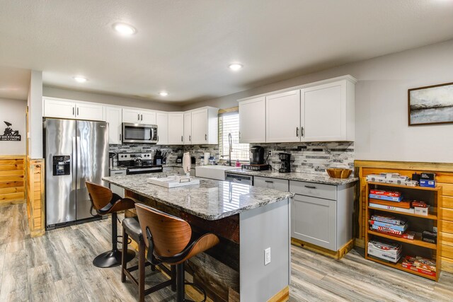 kitchen with appliances with stainless steel finishes, a center island, sink, and light hardwood / wood-style flooring