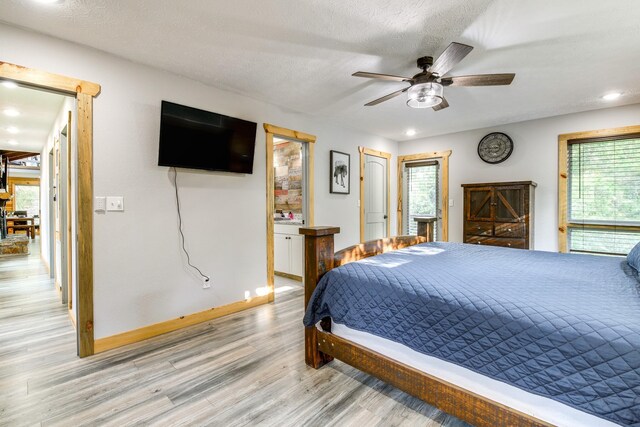 bedroom featuring a textured ceiling, ceiling fan, light wood-type flooring, and multiple windows