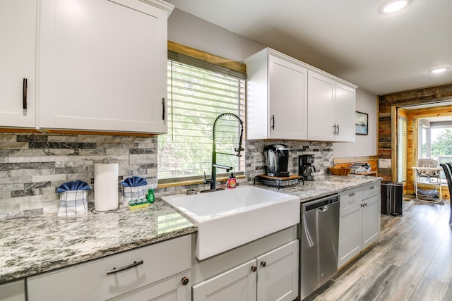 kitchen with stainless steel dishwasher, sink, light wood-type flooring, and white cabinets