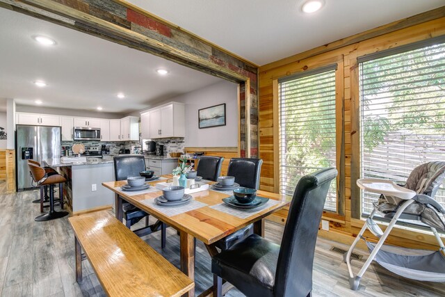 dining area with wooden walls and light hardwood / wood-style floors