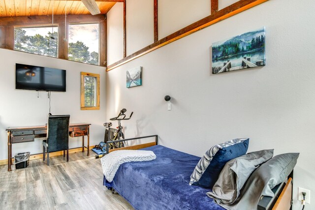 bedroom featuring multiple windows, wood ceiling, hardwood / wood-style flooring, and a towering ceiling