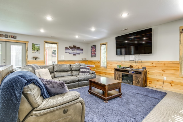 carpeted living room with french doors and wood walls