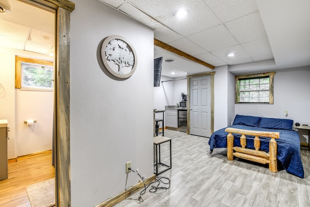 bedroom with a drop ceiling and light hardwood / wood-style floors