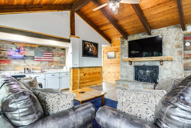 living room with a stone fireplace, wood-type flooring, wooden ceiling, and ceiling fan