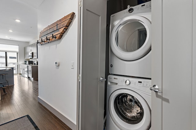 clothes washing area featuring hardwood / wood-style flooring and stacked washer / drying machine