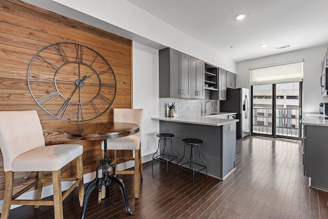 kitchen featuring gray cabinetry, dark hardwood / wood-style floors, backsplash, kitchen peninsula, and sink