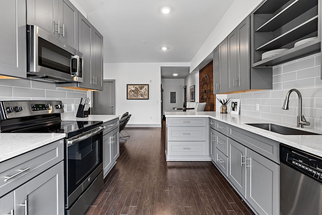 kitchen with tasteful backsplash, dark wood-type flooring, stainless steel appliances, sink, and gray cabinets