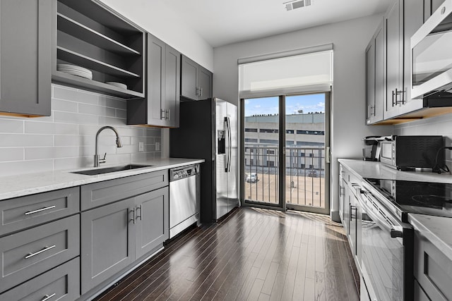 kitchen featuring gray cabinets, light stone counters, sink, dark hardwood / wood-style floors, and appliances with stainless steel finishes