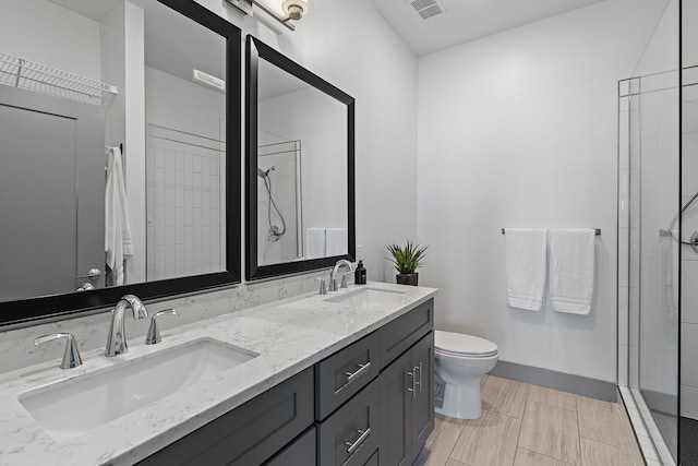 bathroom featuring toilet, a tile shower, and vanity