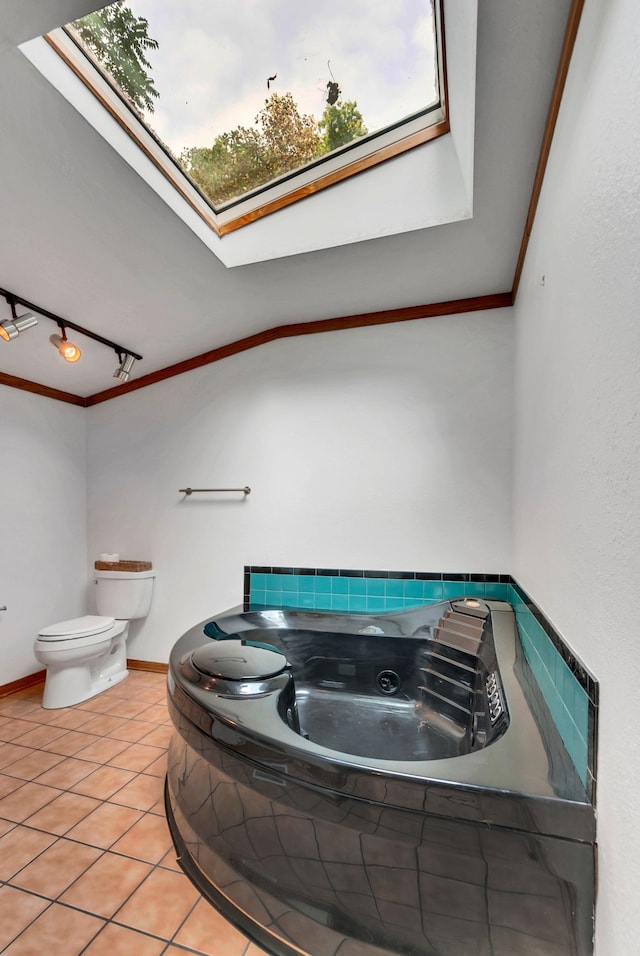 bathroom featuring toilet, a skylight, tile patterned floors, and tiled bath