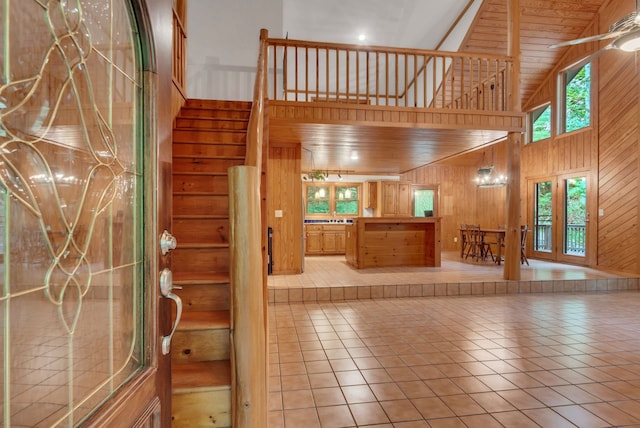 interior space with wood ceiling, high vaulted ceiling, wood walls, and light tile patterned flooring