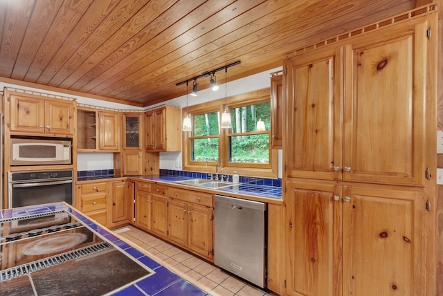 kitchen with pendant lighting, light tile patterned floors, stainless steel appliances, sink, and track lighting