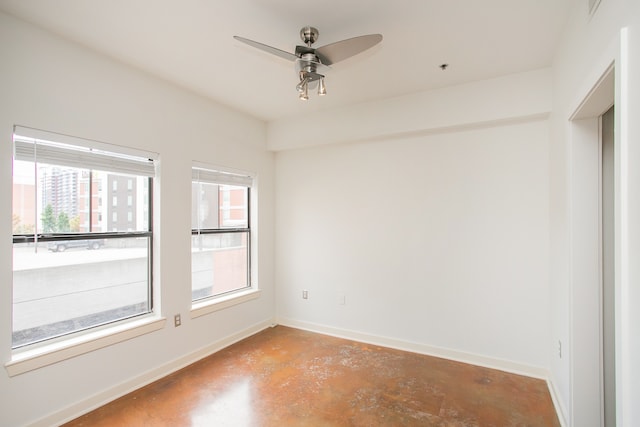 empty room with plenty of natural light, ceiling fan, and concrete flooring