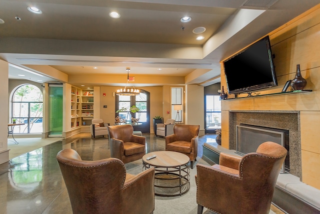 living room featuring built in shelves, plenty of natural light, an inviting chandelier, and a high end fireplace