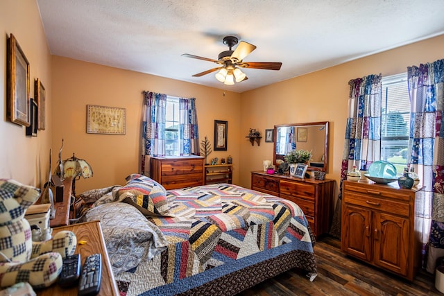 bedroom with a ceiling fan, dark wood-style floors, and a textured ceiling