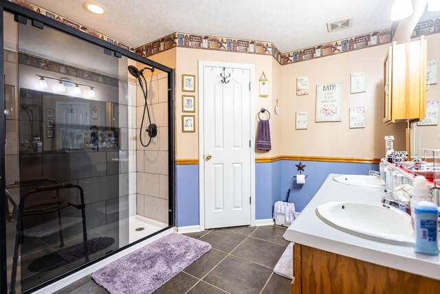 bathroom featuring tile patterned flooring, a stall shower, visible vents, and a sink