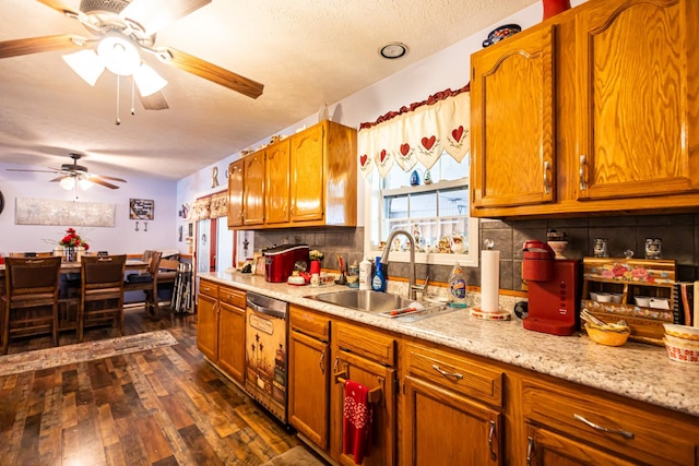 kitchen featuring dark wood-type flooring, a sink, stainless steel dishwasher, light countertops, and decorative backsplash