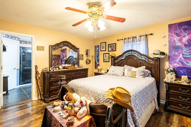 bedroom featuring dark wood finished floors, a ceiling fan, baseboards, and ensuite bathroom