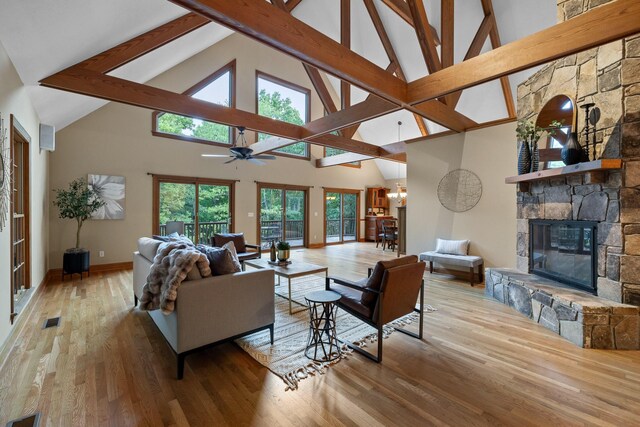 living room with a fireplace, light hardwood / wood-style floors, ceiling fan, beamed ceiling, and high vaulted ceiling