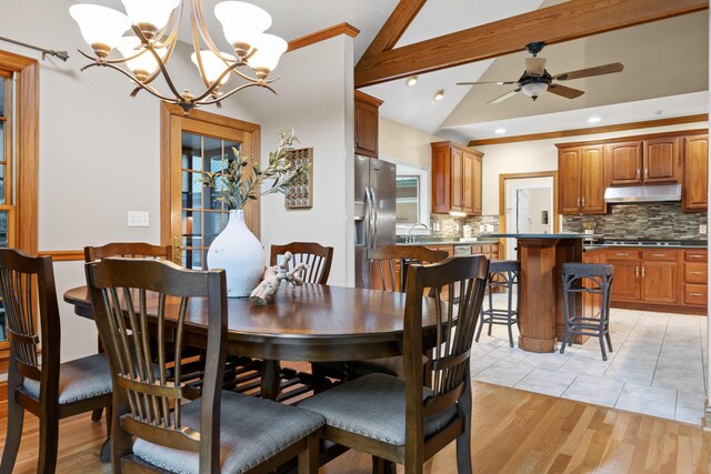 dining room with sink, crown molding, lofted ceiling with beams, light wood-type flooring, and ceiling fan with notable chandelier