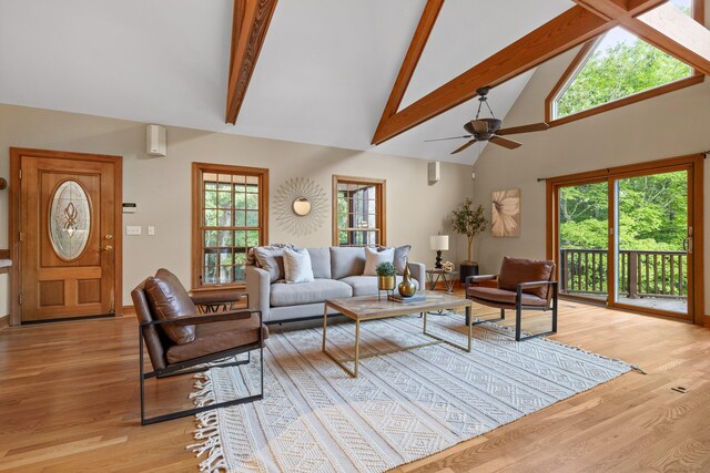 living room featuring light hardwood / wood-style floors, high vaulted ceiling, beamed ceiling, and ceiling fan