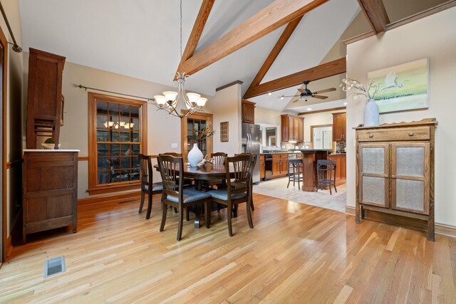 dining area featuring beam ceiling, high vaulted ceiling, ceiling fan with notable chandelier, and light wood-type flooring