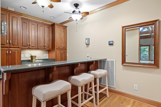 bar with light hardwood / wood-style flooring, ornamental molding, and ceiling fan